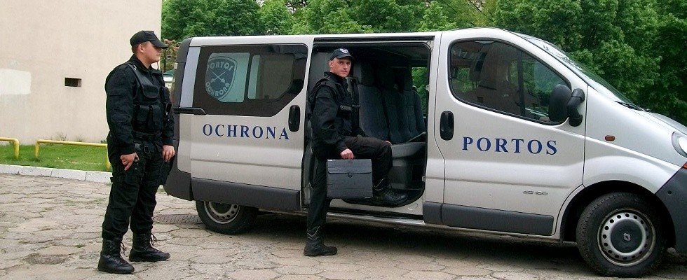 Pracownicy Ochrona Portos wsiadający do srebrnego służbowego samochodu typu Van