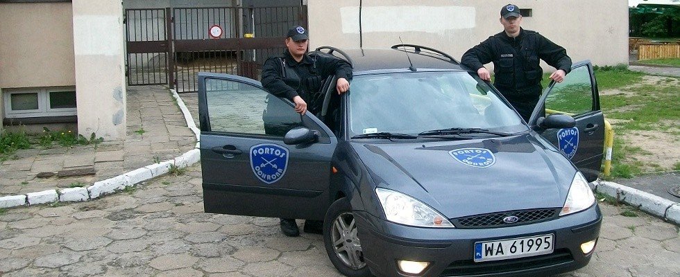 Pracownicy Ochrona Portos wsiadający do granatowego samochodu służbowego